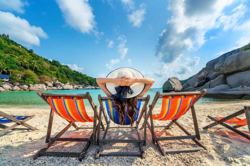 Woman with hat sitting on chairs beach in beautiful tropical beach - jigsaw puzzle