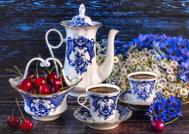 Ein Korb mit Kirschen Tassen Kaffee eine Kaffeekanne ein Strauß Wildblumen