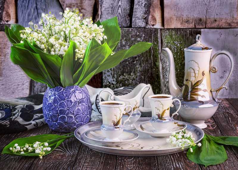 青い花瓶に入ったスズランの花束とコーヒーカップ
