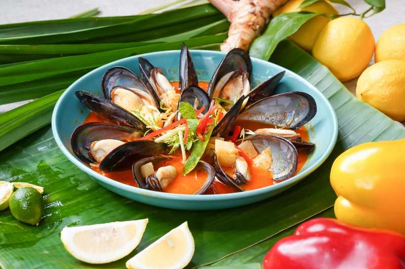 a bowl of steamed mussels on a banana leaf