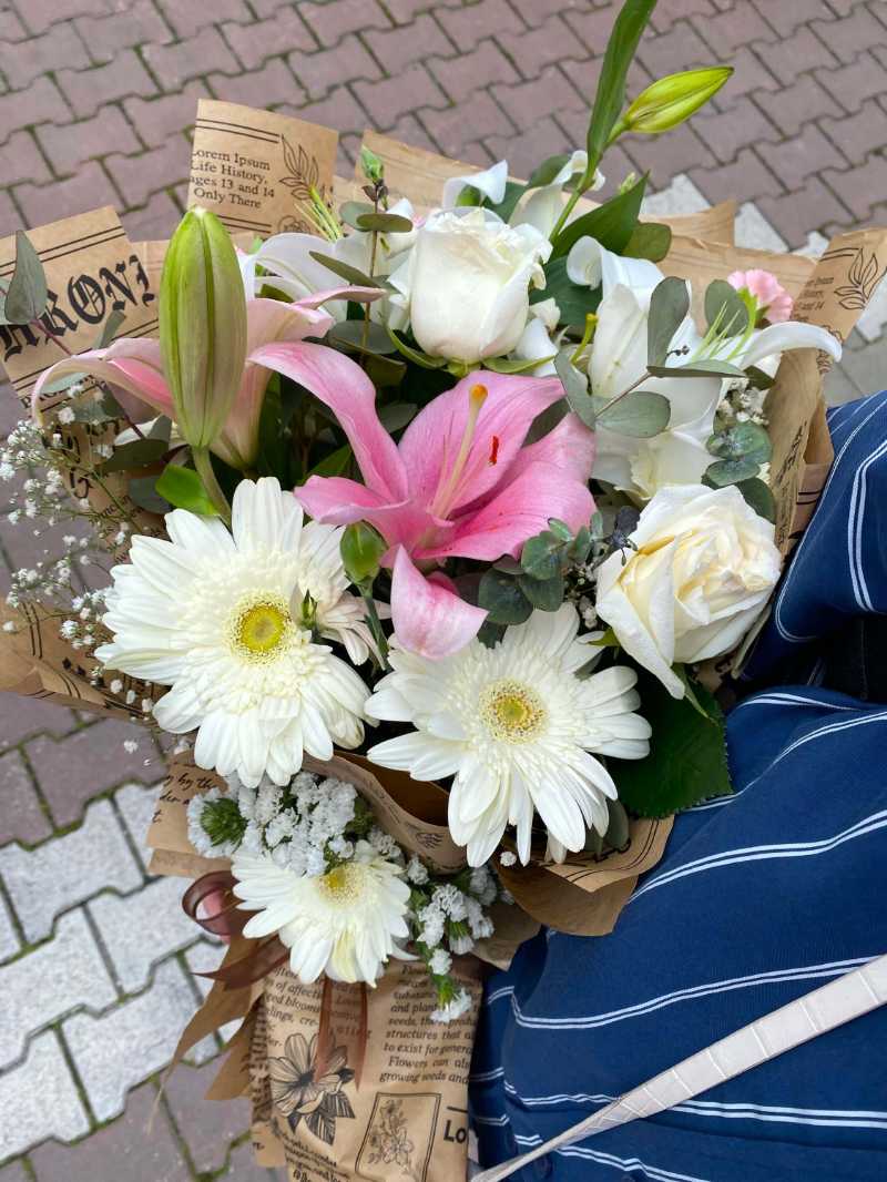 A colorful bouquet of mixed flowers wrapped in newspaper