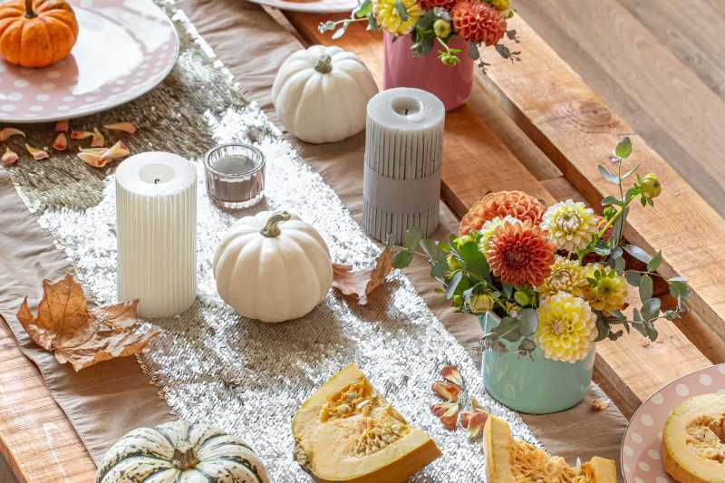 Uma mesa de jantar festiva de outono com abóboras flores e velas.