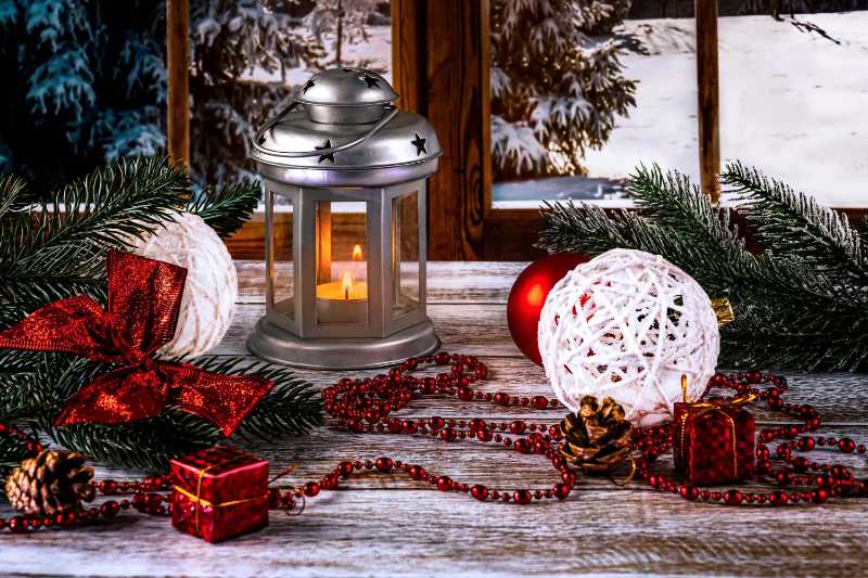 A silver lantern with a candle on the background of the window christmas red and white balls