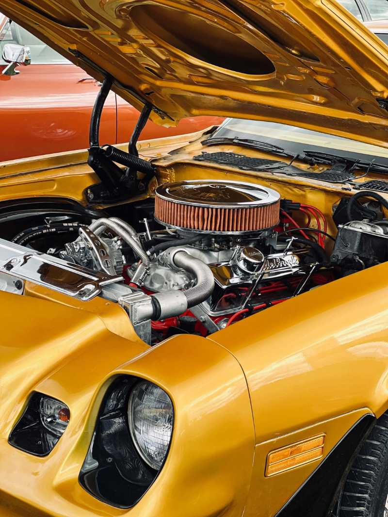 a vintage golden muscle car engine with hood open