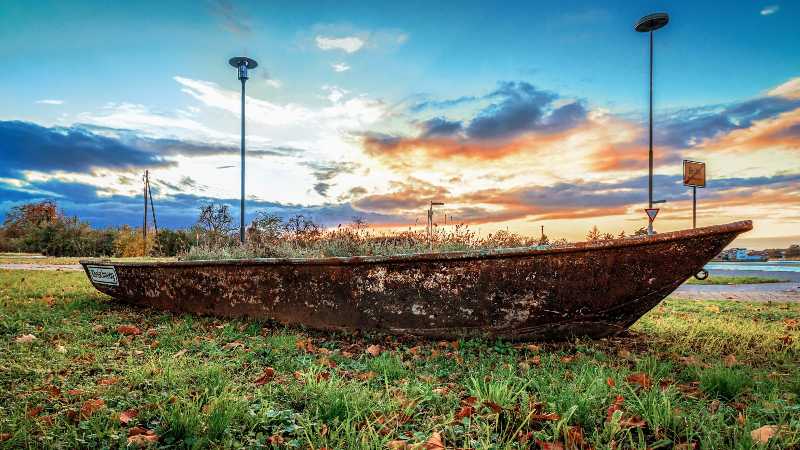 Abandoned Rusty Boat on Land Under a Dramatic Sunset Sky