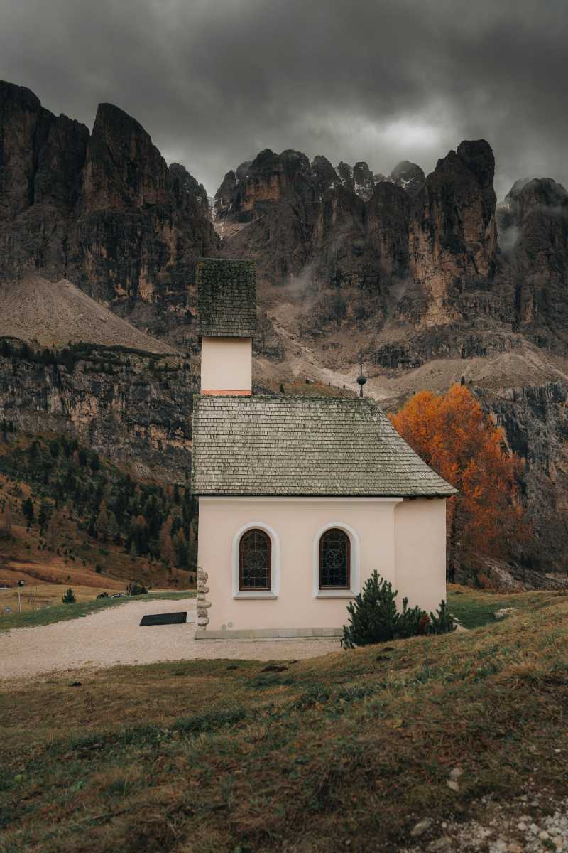 a small church in a field with mountains in the background - jigsaw puzzle