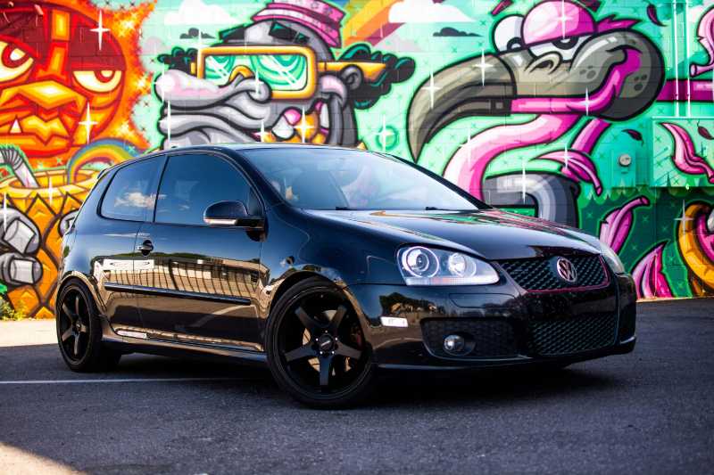 Black Golf GTI with Black Rims Against Vibrant Graffiti Art