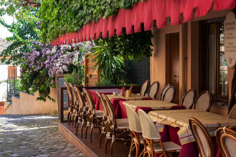 Charming outdoor cafe terrace with red canopy and wicker chairs
