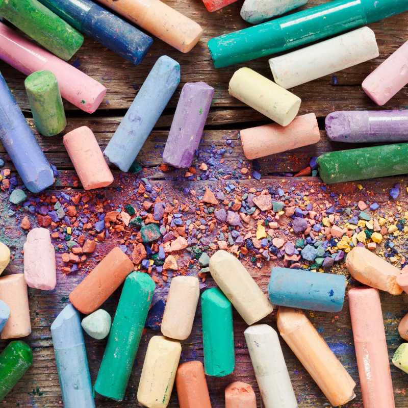 Raccolta di pastelli color arcobaleno su una vecchia scrivania di legno