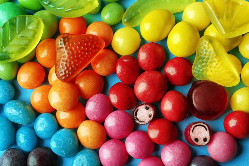 Bunte Bonbons und Gummibärchen auf blauem Hintergrund