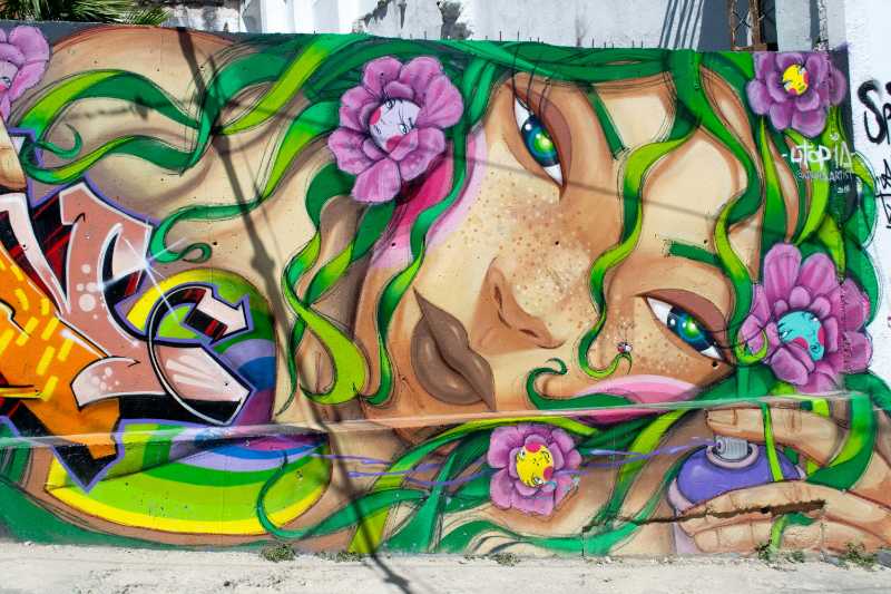 Mural de grafite colorido com mulher e latas de tinta