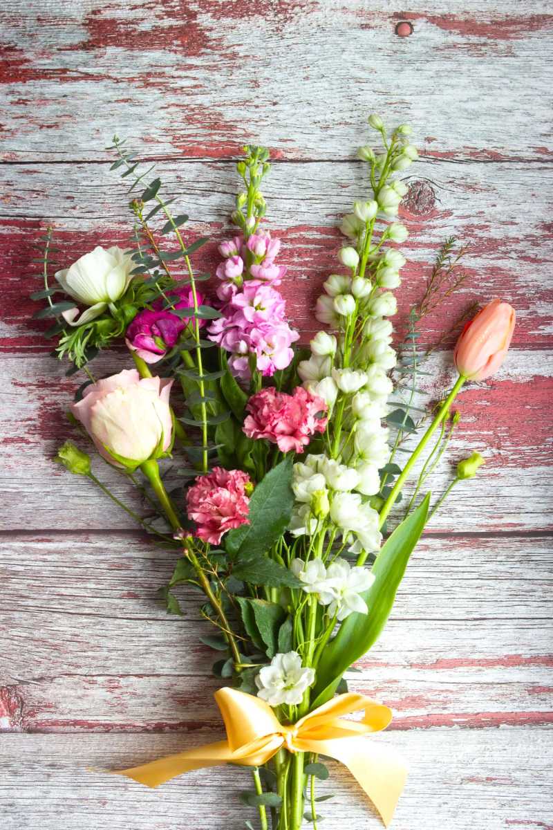 Delicate mixed flowers on brown wooden surface