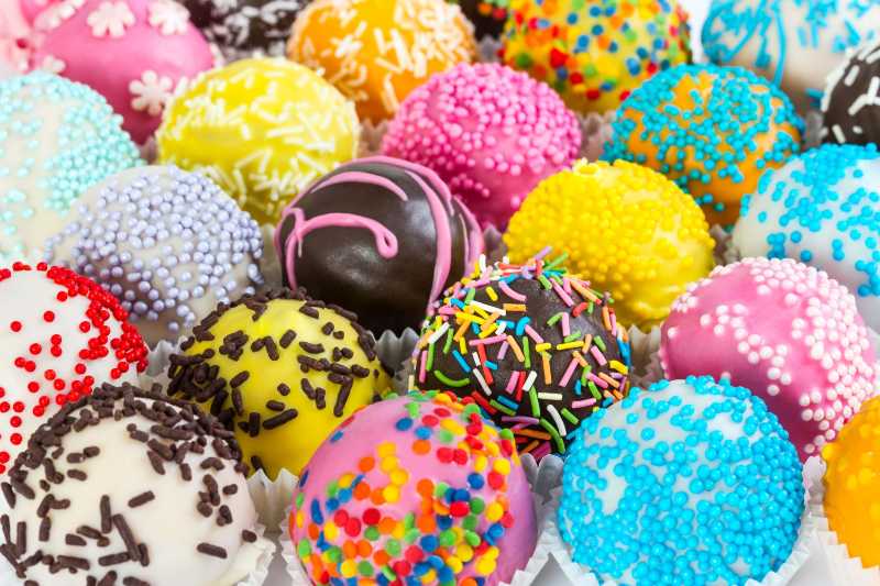 Different colorful cake balls with decorative sprinkles and icing