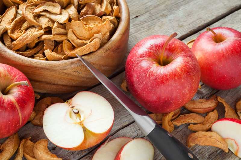 Getrocknete Apfelscheiben und frische Apfelfrüchte auf dem Küchentisch