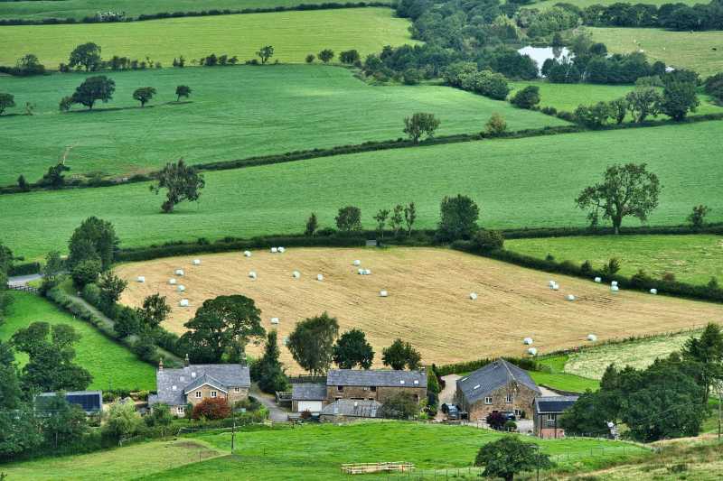 Idyllic English Countryside Farm View with Hay Bales and Rolling Green Fields