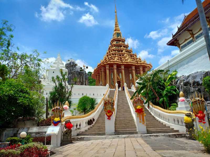 Golden Thai Buddhist temple with grand naga staircase and white stupas