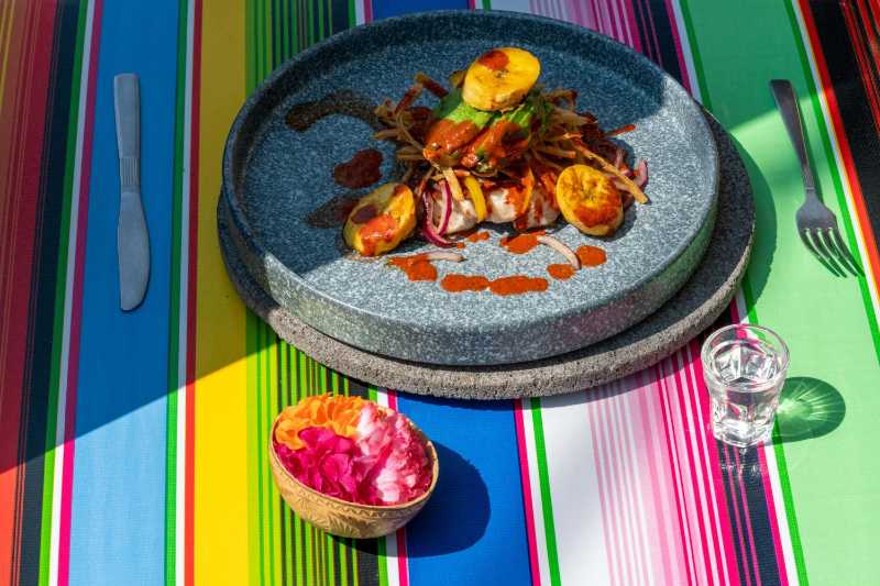 Gourmet Mexican cuisine on a stone plate with colorful striped background
