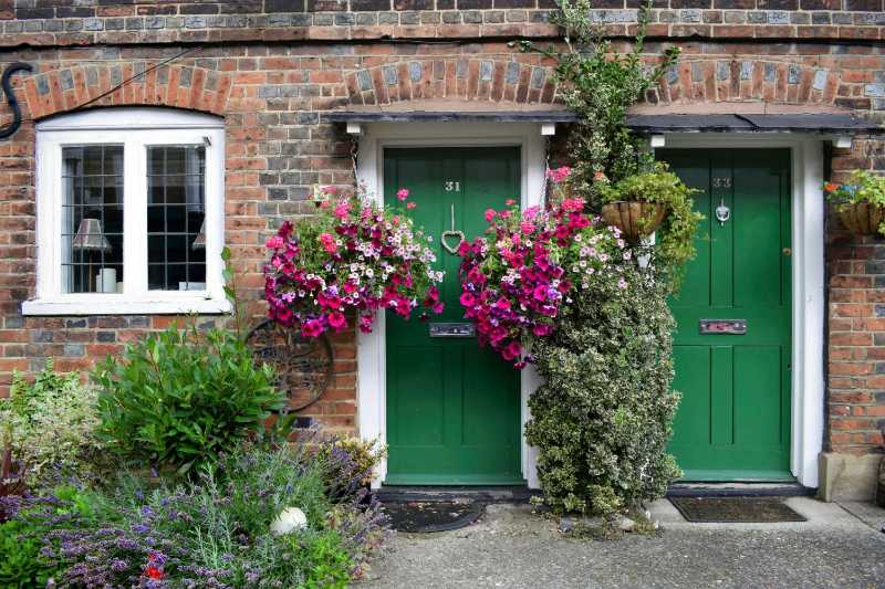 Green Wooden Doors on a Brick House with Flowers and Plants