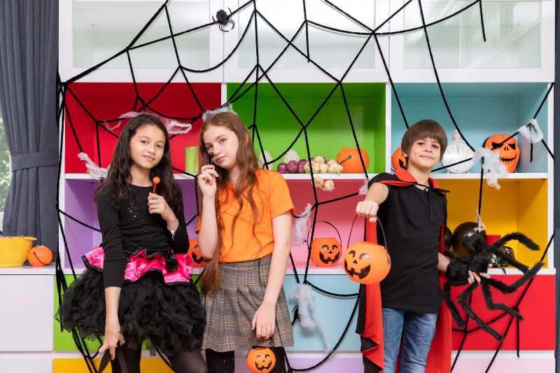 Happy children boy and girls standing front of halloween party decoration and holding pumpkin jack-o'-lantern