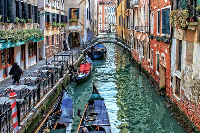 Puente de góndolas y coloridos edificios históricos en el canal oculto de Venecia