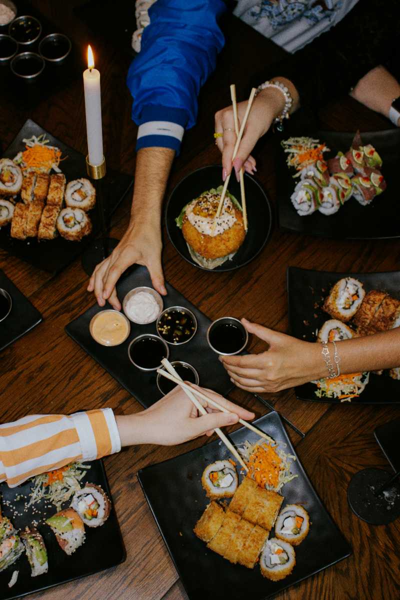 a group of people sitting around a table eating sushi - jigsaw puzzle