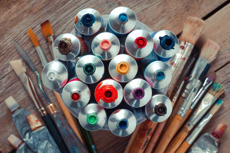 木製の机の上の油性多色絵の具チューブのクローズアップとアーティストの絵筆