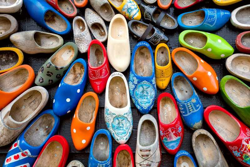 Velhos sapatos holandeses de madeira klomps muitos clomps velhos e coloridos contra o fundo de uma parede de madeira lembranças populares tradições da Holanda