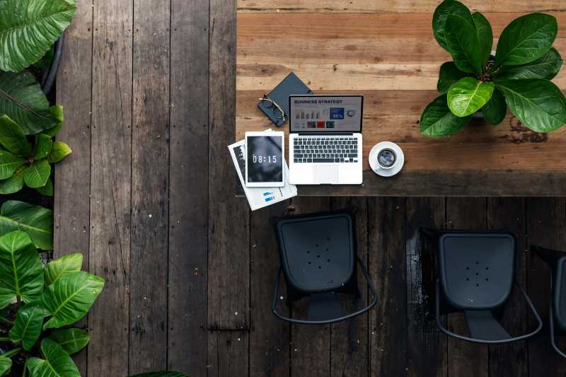Outdoor Office Setup Business Planning on Wooden Deck with Greenery