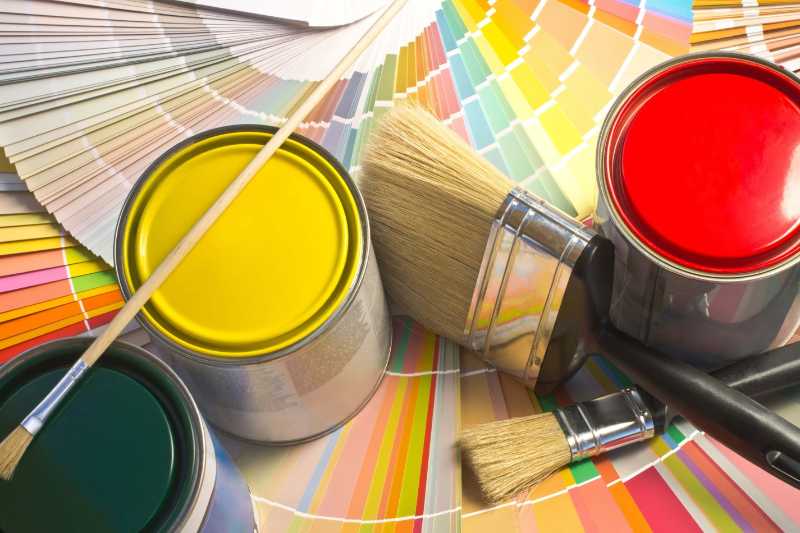 Paint cans and brushes on colorful paint samples fan