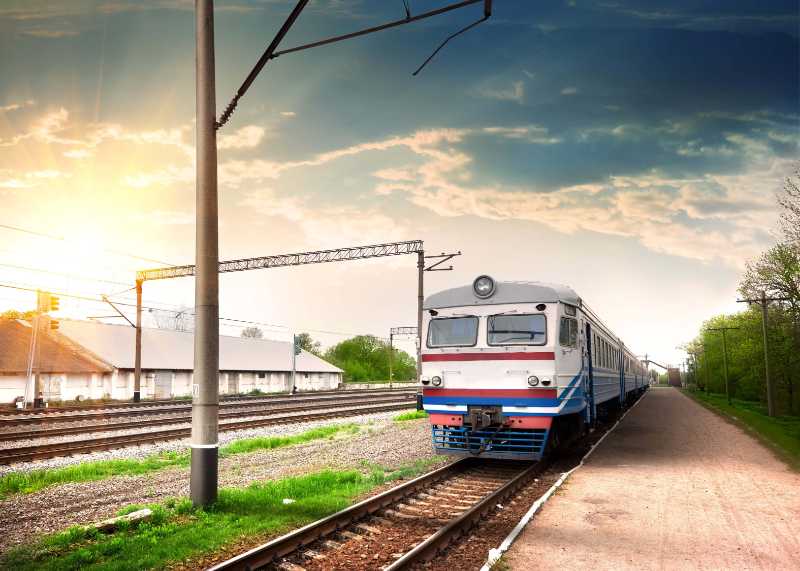 Passenger Train Arriving at a Rural Railway Station at Sunset