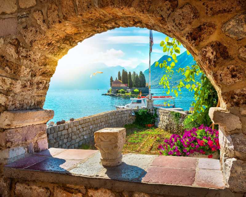 Scenic View of Our Lady of the Rocks Through a Stone Archway