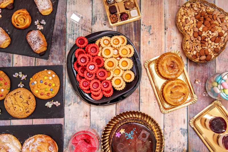 Set of pastry plates with cookies sacher chocolate cake apple tart nuts chocolates and jelly beans