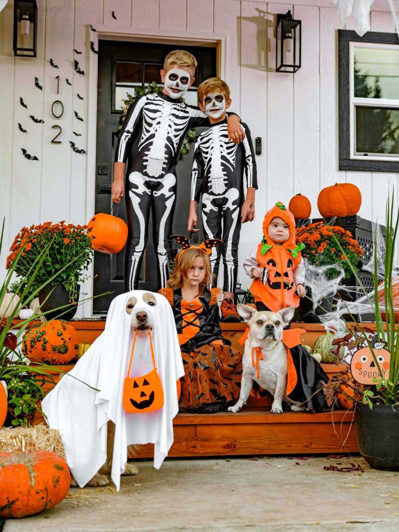 Gruselige Halloween-Veranda mit kostümierten Kindern und Haustieren