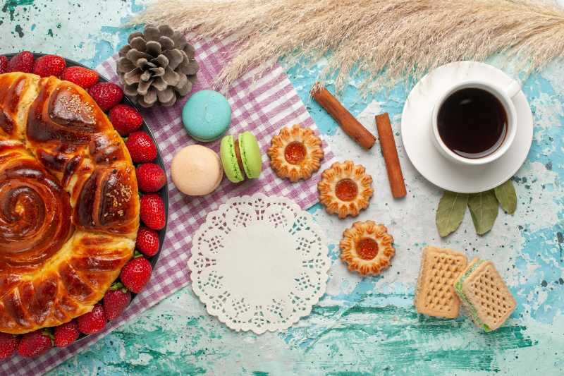 Torta de morango com biscoitos e macarons franceses na mesa azul