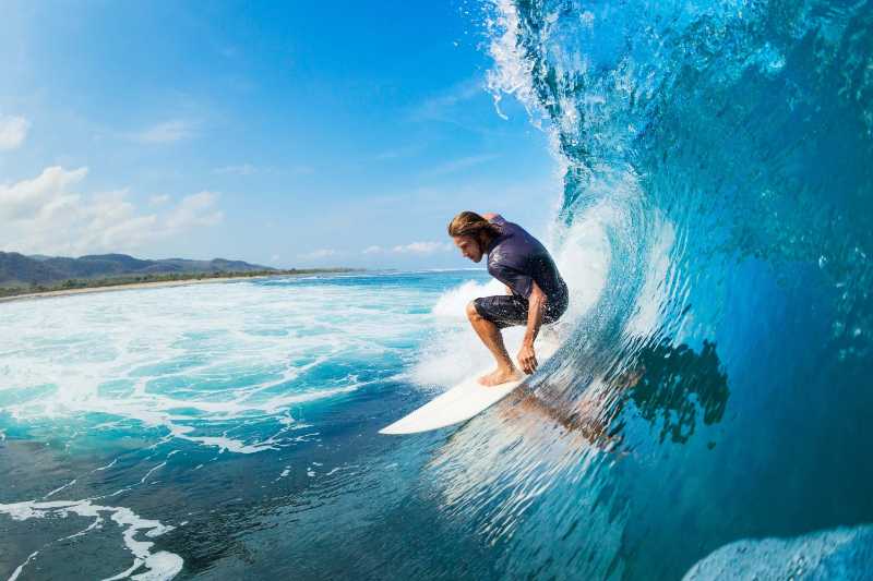 Surfer on a white surfboard catching a tropical blue wave