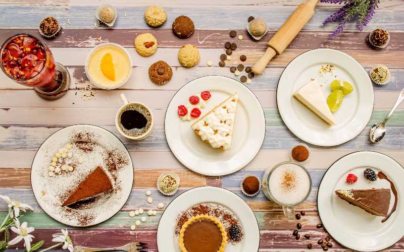 Table with various cookies donuts cakes cheesecakes and desserts on white background delicious