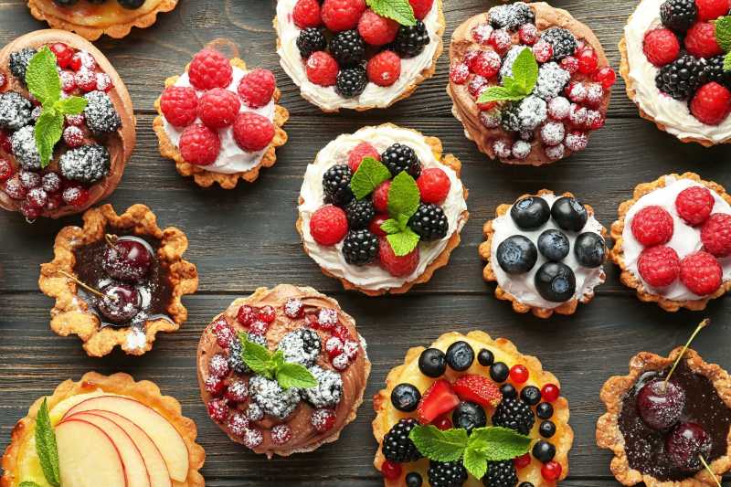Leckere Törtchen mit Beeren auf Holzhintergrund