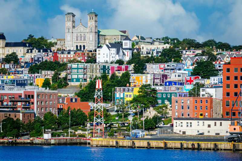 the basilica of st john the baptist stands tall above the colorful neighborhoods above the piers of st johns newfoundland