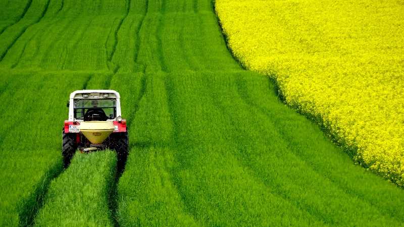 Trator trabalhando em campo agrícola verde e amarelo vibrante