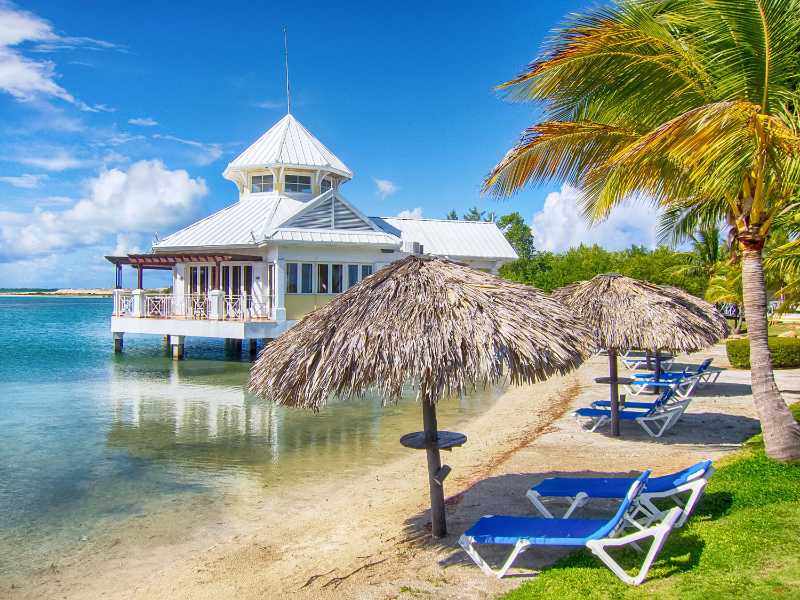 Resort de playa tropical con bungalow sobre el agua y palmeras