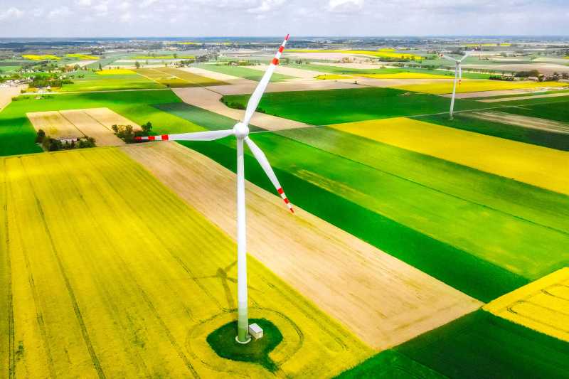 Vibrant Contrast White Wind Turbine on Bright Yellow and Green Fields