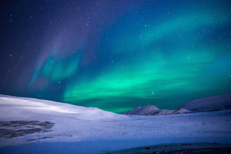 Vibrant Green Northern Lights aAurora Borealis over Snow Landscape