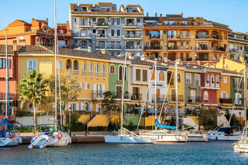 Vibrant marina with colorful buildings and docked boats in Port Saplaya