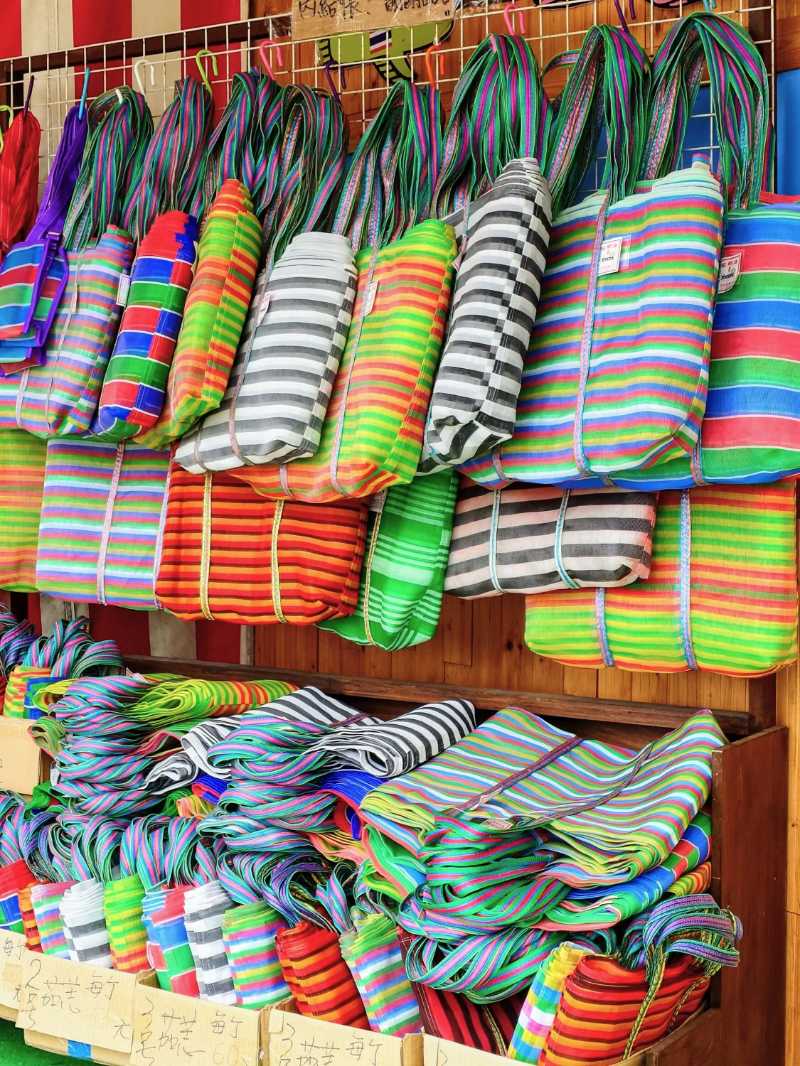 Exhibición de bolsos con rayas vibrantes en un puesto de mercado