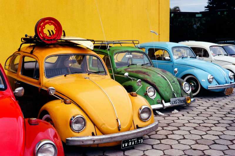 Volkswagen beetle cars parked near a yellow wall