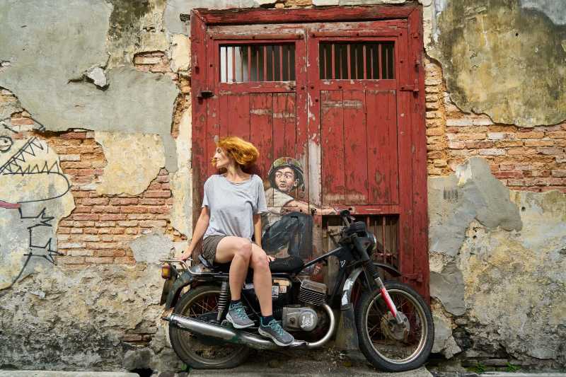 Woman on a Vintage Motorcycle in Front of a Street Art Mural