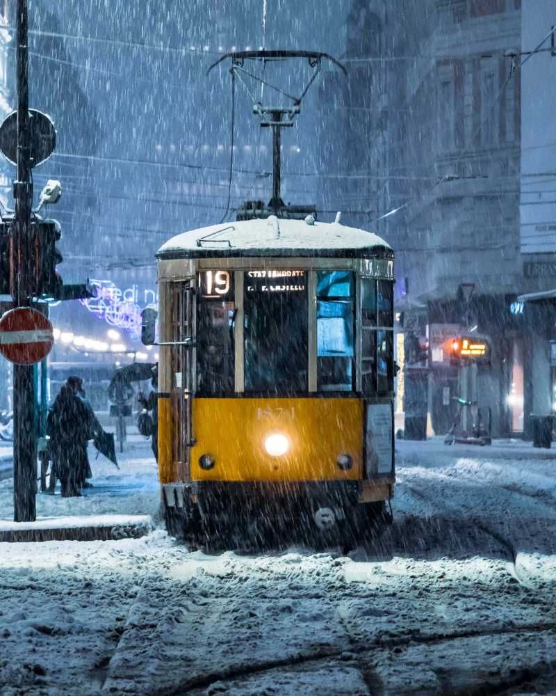 Tranvía amarillo moviéndose por una calle nevada de la ciudad